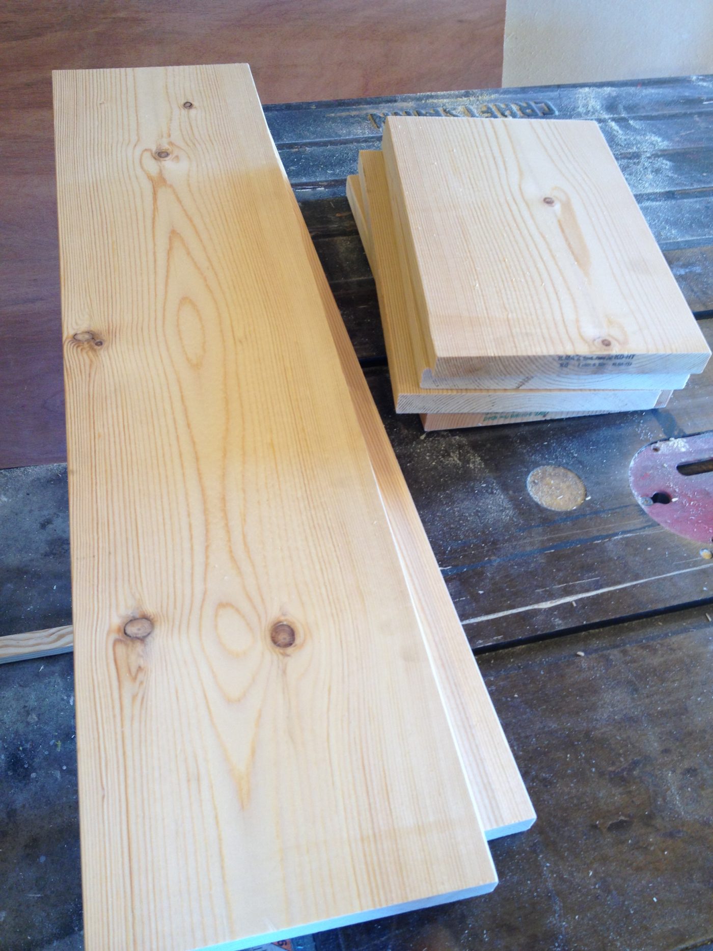 1x8 board cut into pieces to assemble floating shelves--two 28" boards and four 10" boards on workbench