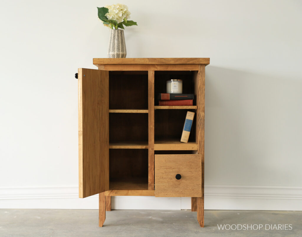Small cabinet with door open showing adjustable shelves on each side of middle divider