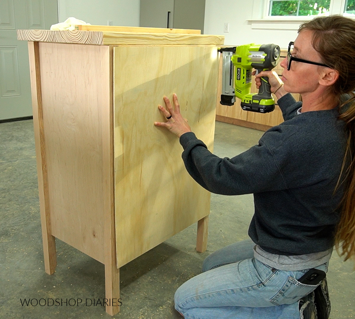 Shara Woodshop Diaries stapling back panel onto cabinet