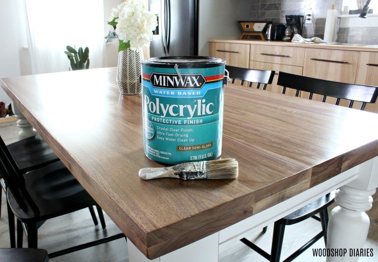 Can of polycrylic sitting on walnut table with soft semi gloss finish and a paintbrush