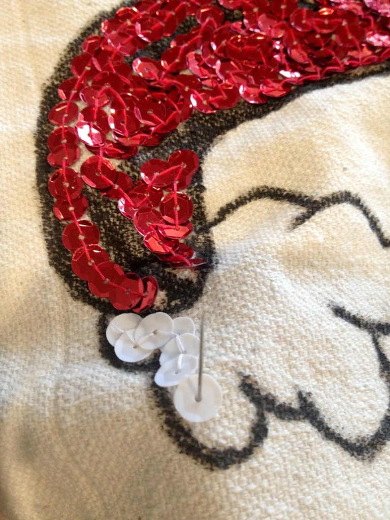 Close up of needed stitching sequins onto fabric