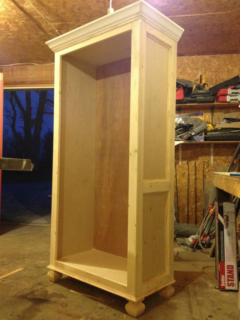 Unfinished tall bookshelf in workshop before adding shelves--trimmed out on the sides with 1x3s and cove molding