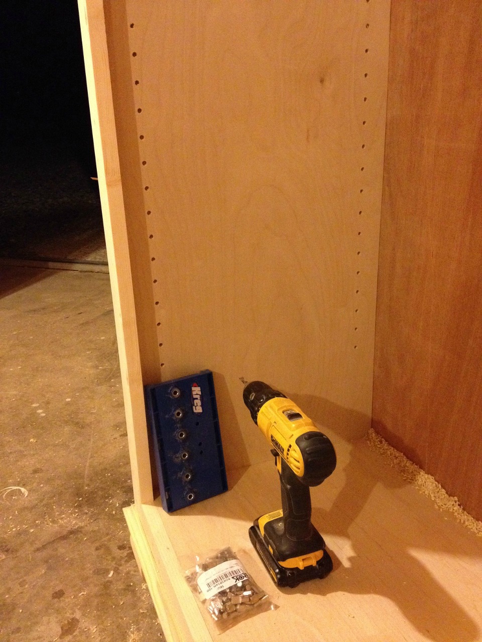 Shelf pins drilled into sides of free standing bookshelf with Kreg shelf pin jig