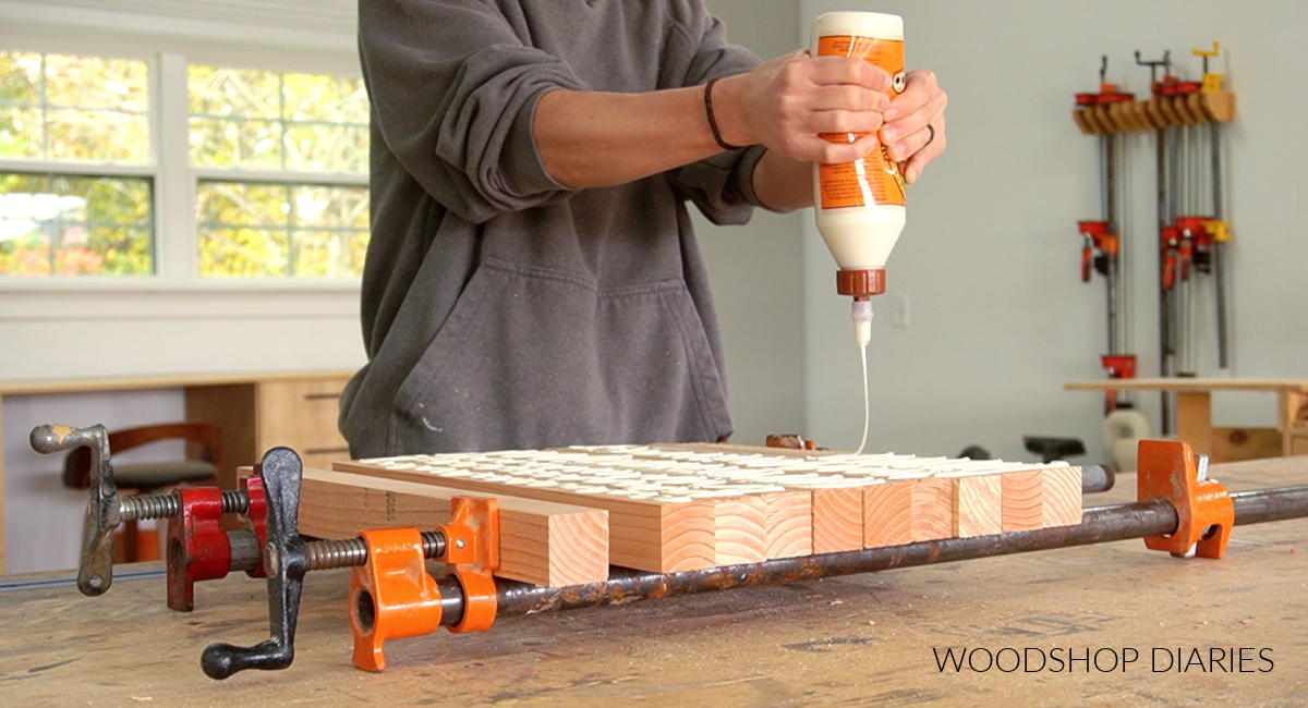 Shara Woodshop Diaries applying wood glue to 2x2s in pipe clamps