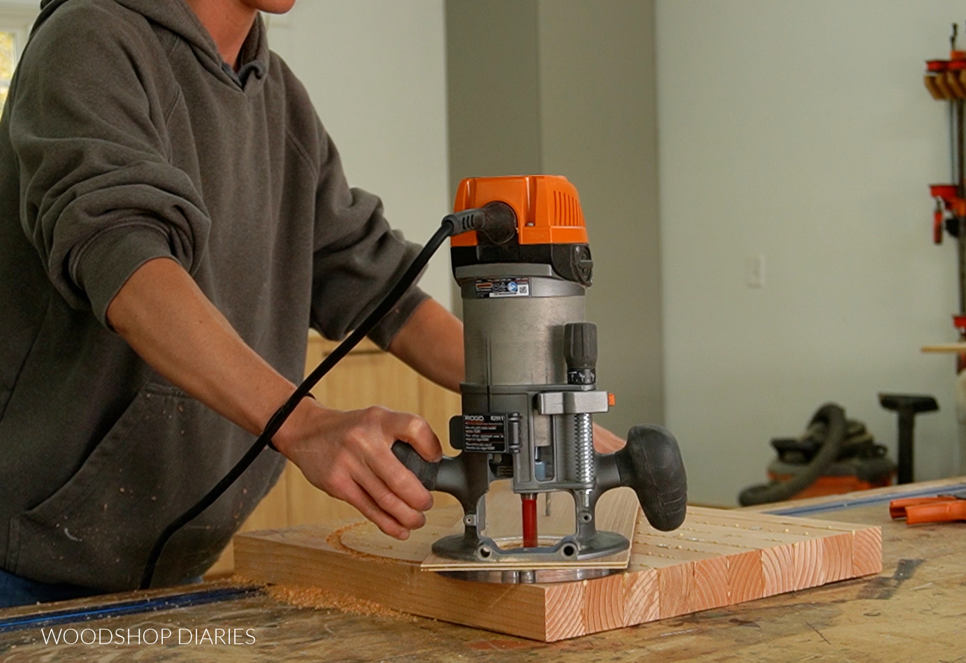 Using router and homemade circle jig to cut out round lazy susan on wooden panel on workbench