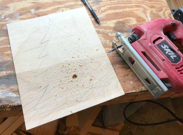 Christmas tree drawn on piece of wood with hole drilled to be cut out using jigsaw