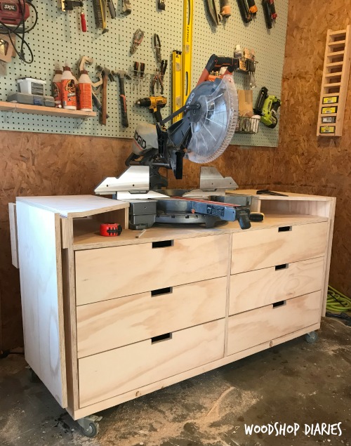 DIY mobile miter saw stand with folding wings and storage drawers in workshop