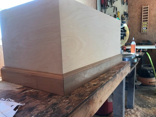 Mitered baseboard along bottom of storage trunk box