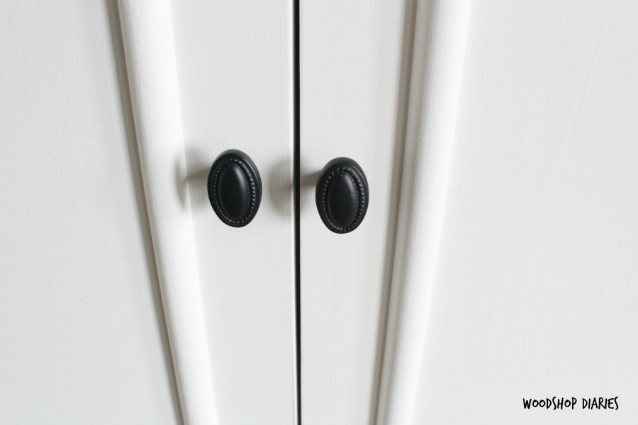 Close up of armoire cabinet knobs--black knobs against white painted wood doors