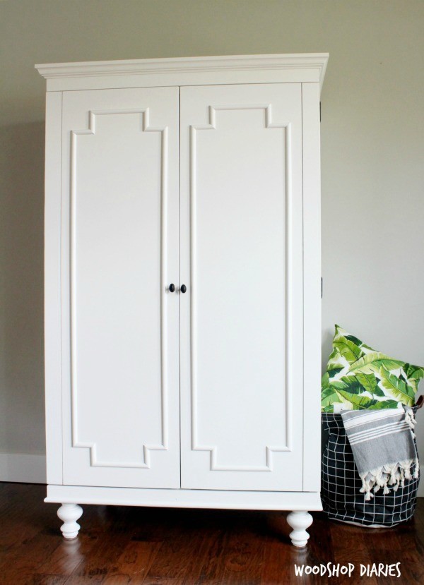 Decorative armoire storage cabinet painted white with large double doors with decorative trim on front