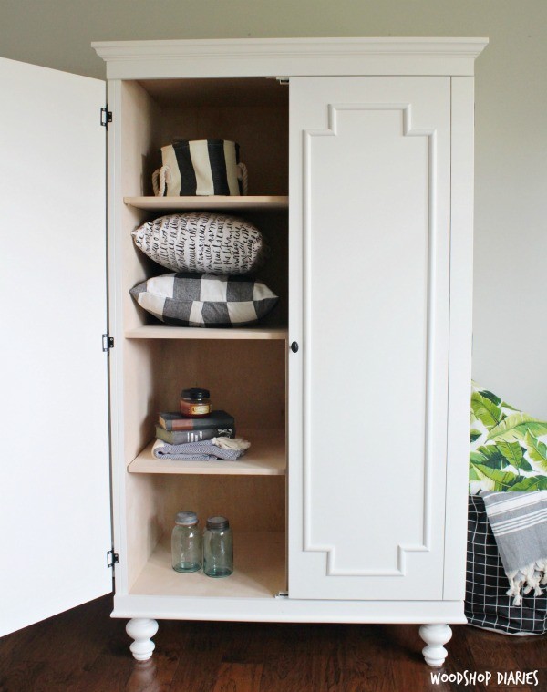 White and wood tall DIY armoire cabinet with double doors and decorative feet. One door open one door closed