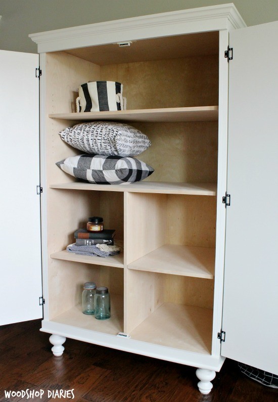 White painted plywood storage armoire cabinet with doors open and adjustable shelves inside