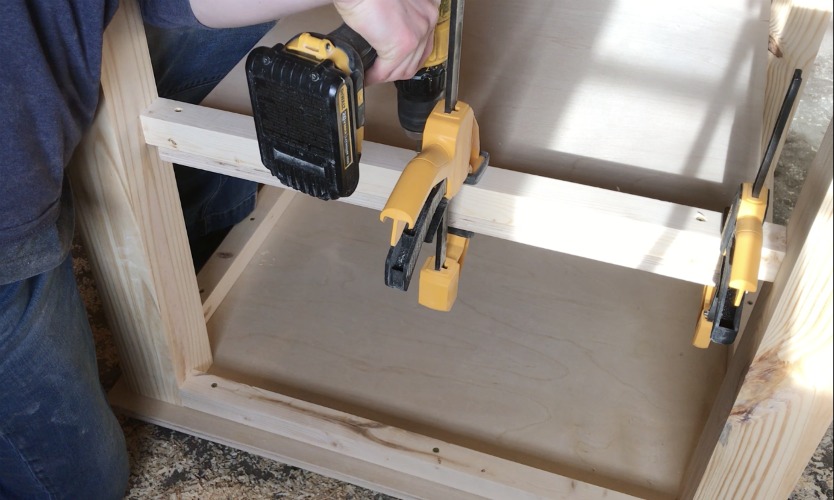 Using a drill to secure shelf to frame of kids toddler table