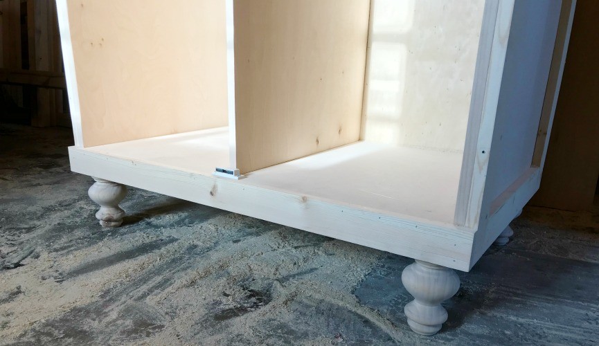 Decorative feet installed onto bottom corners of armoire cabinet