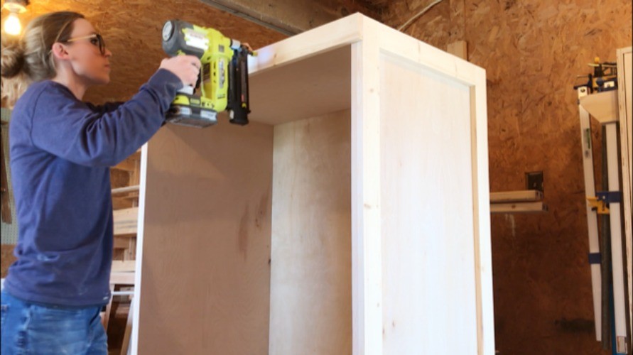 Shara Woodshop Diaries brad nailing trim pieces along top edge of cabinet 