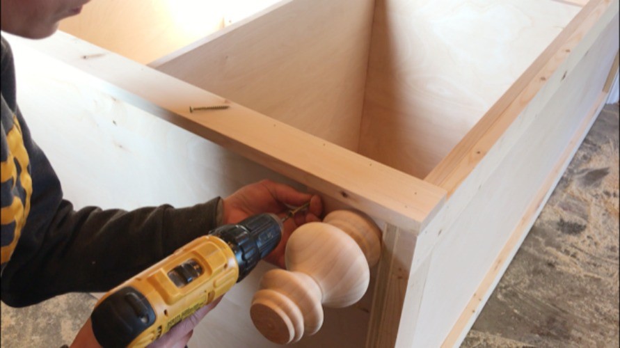Shara Woodshop Diaries using wood screws to install spacer blocks onto bottom corner of armoire cabinet