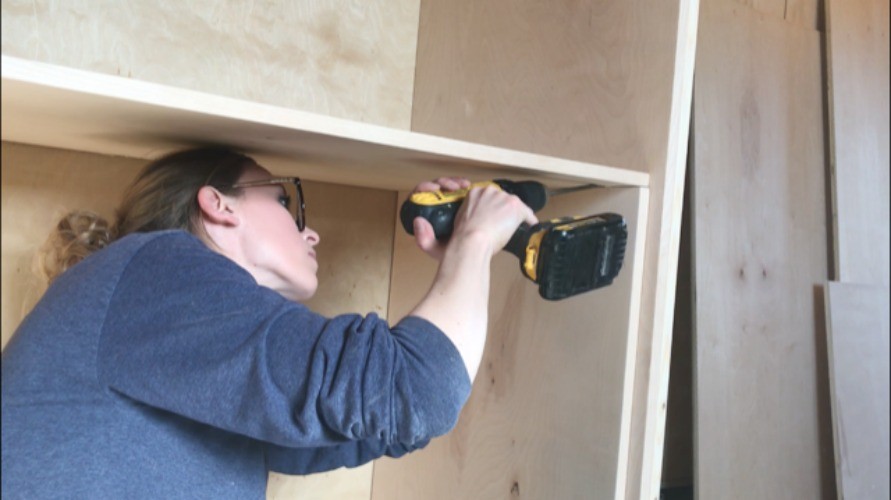 Shara Woodshop Diaries installing middle divider panel into cabinet using pocket hole screws
