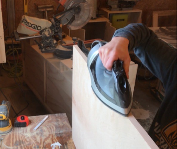using an iron to apply iron on edge banding to plywood panel