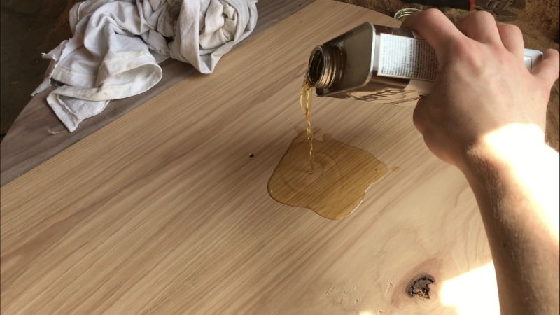 Pouring Danish oil onto hickory and walnut wood clock