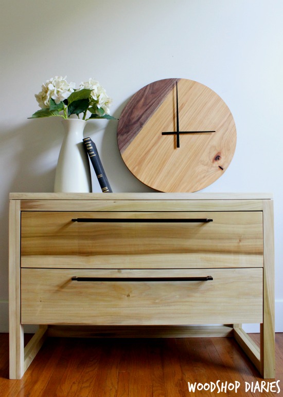 Two tone DIY wood clock sitting on modern two drawer nightstand with vase and book