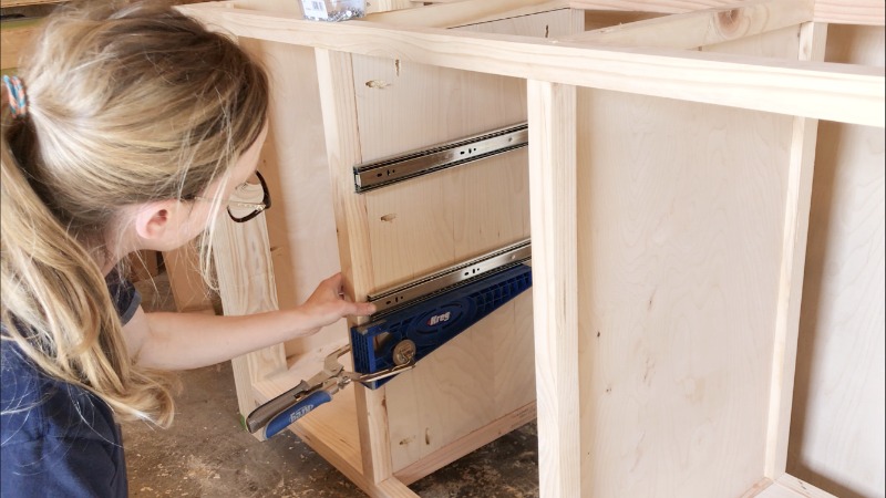 Kreg Drawer Slide Jig clamped onto cabinet with drawer slide on top