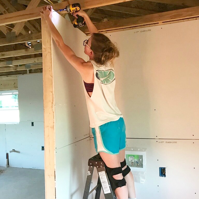 Shara Woodshop Diaries using small ladder to install drywall in laundry nook of garage apartment