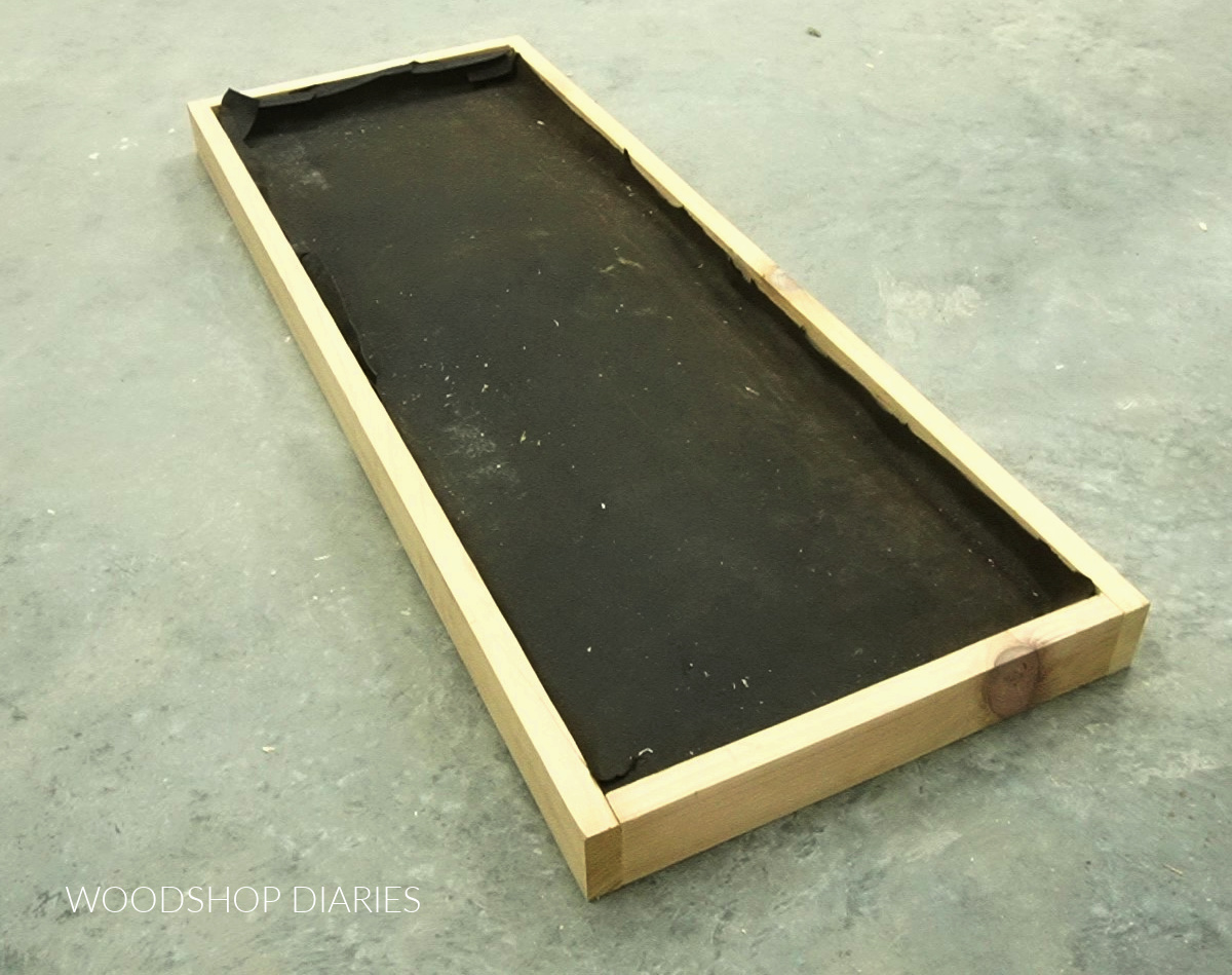 Tar paper placed inside boot tray frame on concrete floor