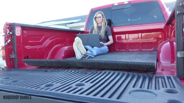 Shara sitting in the back of her red pickup truck working on her laptop