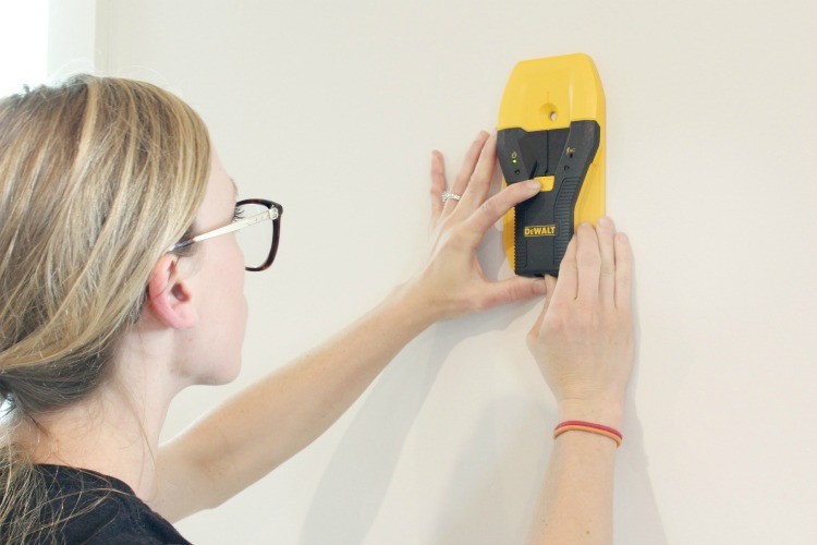 Using stud finder to find studs to hang wall art and shelves--gift idea for new homeowner
