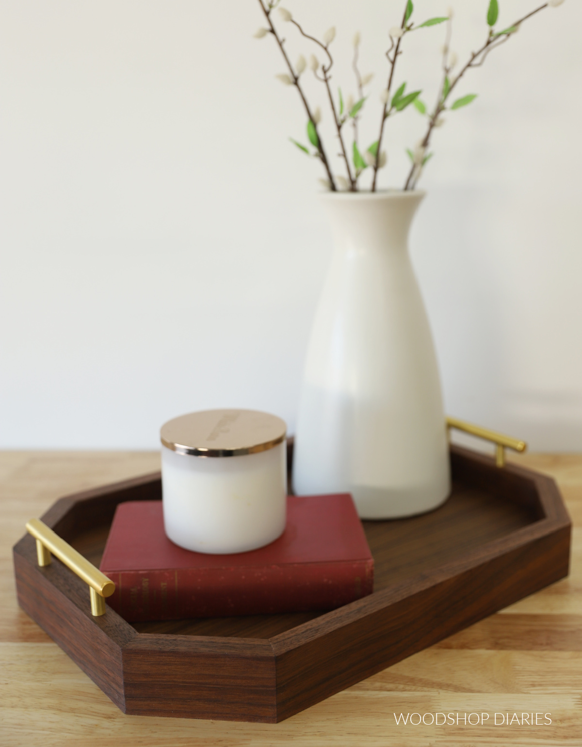 Completed walnut modern DIY serving tray with book, vase, and candle on butcherblock countertop