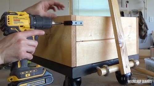 Screw corner braces on DIY wooden wagon for extra industrial style