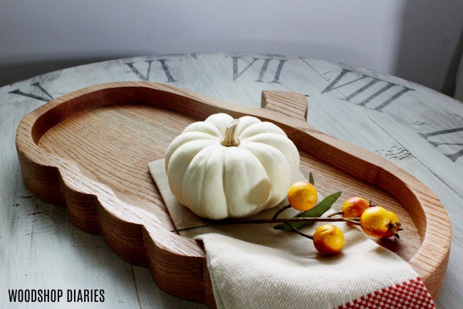 DIY pumpkin tray with white pumpkin and cloth napkin sitting on it on top of coffee table.