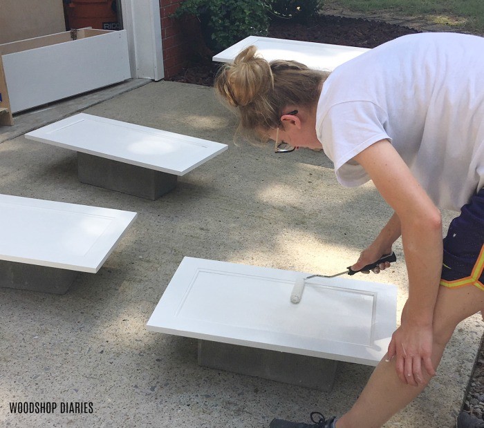 Shara Woodshop Diaries rolling paint onto cabinet doors in driveway