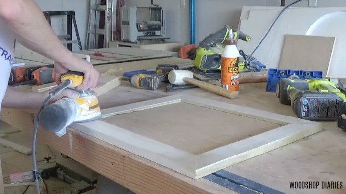 Sanding cabinet door on workbench