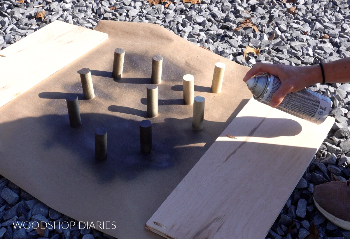 Shara Woodshop Diaries applying black spray paint to hat rack pegs