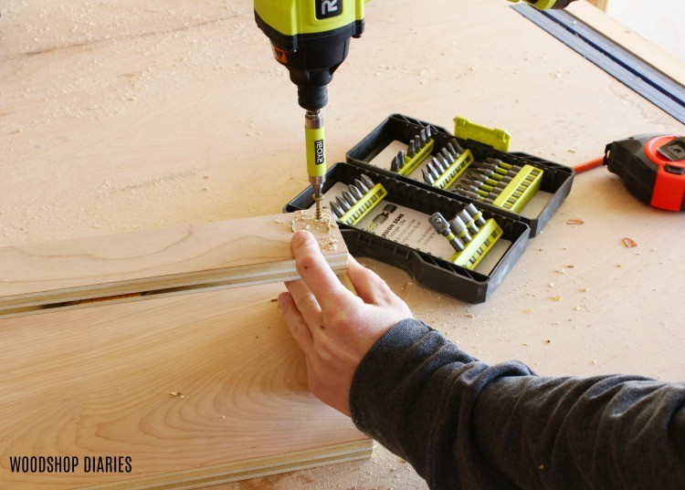 Using a driver to drive a screw into a plywood rack