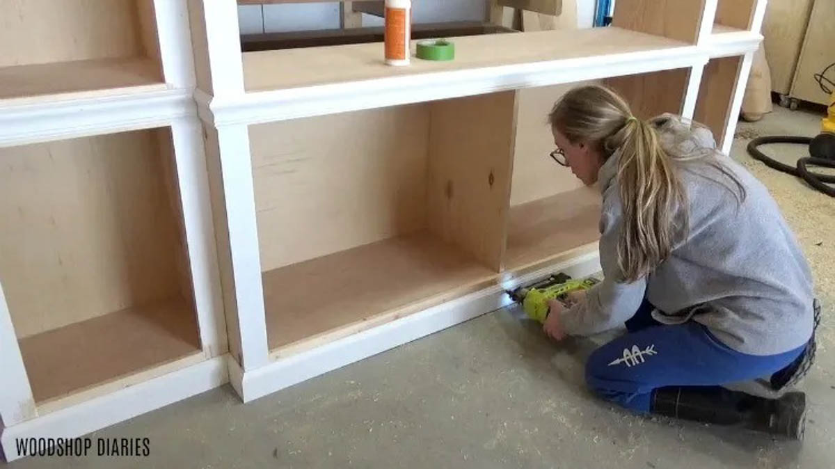 nail baseboard onto middle DIY entertainment center cabinet bottom