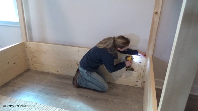 Shara installing back panel of house bed with pocket holes and screws