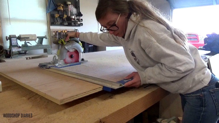 Shara trimming down plywood sheet with circular saw to build sliding door of dog crate