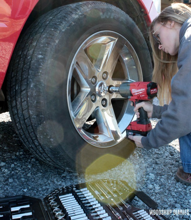 Shara using impact wrench to loosen lug nuts on truck wheel