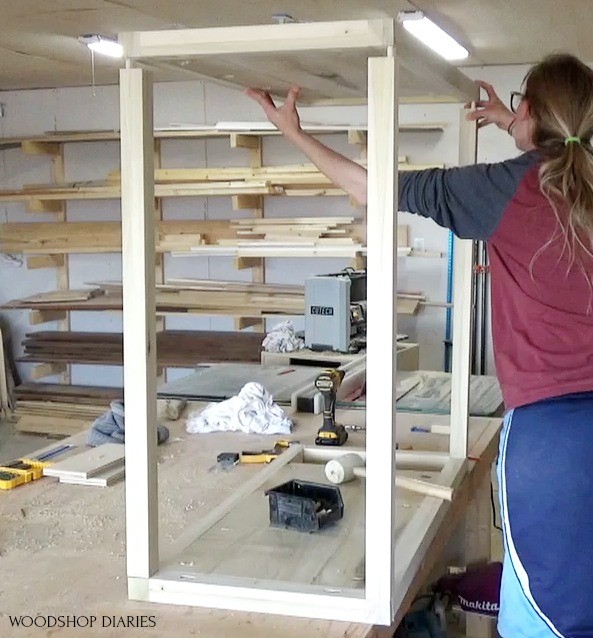 Shara installing side panel onto dresser frame on top of workbench--using wood glue and dowels to assemble