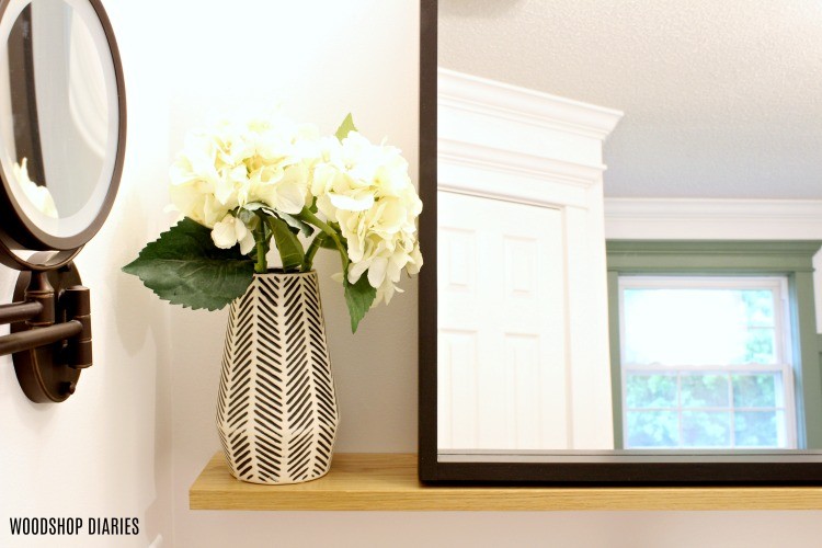 Close up of floating mirror shelf corner with vase and flowers on shelf