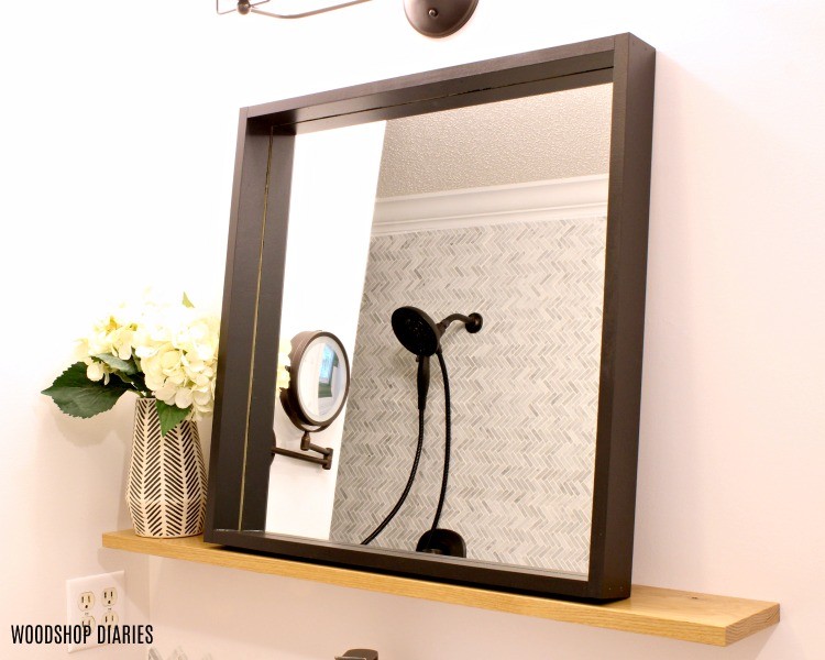 Modern black frame mirror with natural wood floating shelf