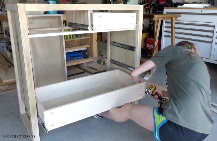 Shara installing bottom dresser drawer into dresser frame using foot as support to hold drawer