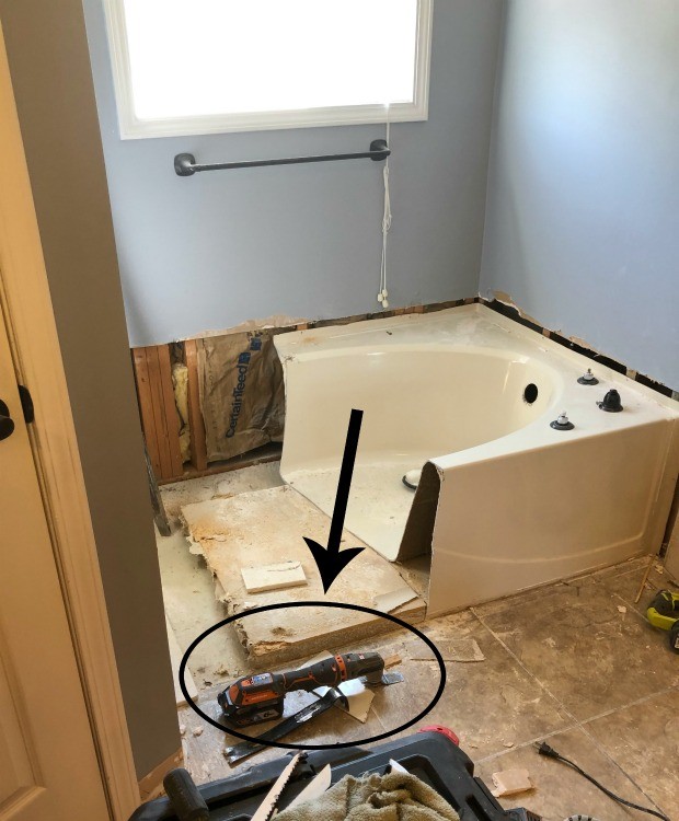 Oscillating saw used to cut through fiberglass tub during bathroom remodel demolition