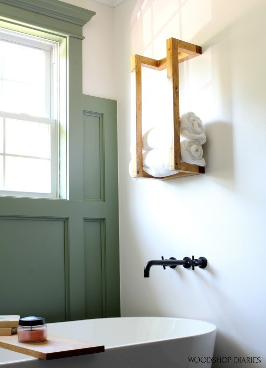 Close up of scrap wood towel rack hanging on wall above bathroom in renovated bathroom