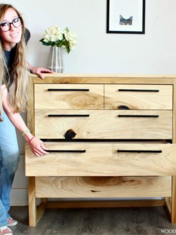 Shara standing next to modern 5 drawer dresser with next to the bottom dresser open