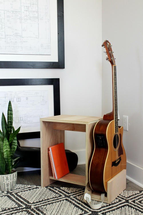 Scrap plywood guitar stand and stool sitting in corner of music room with acoustic guitar in place