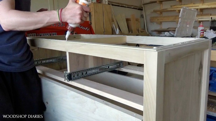 Shara applying wood glue to top of dresser frame