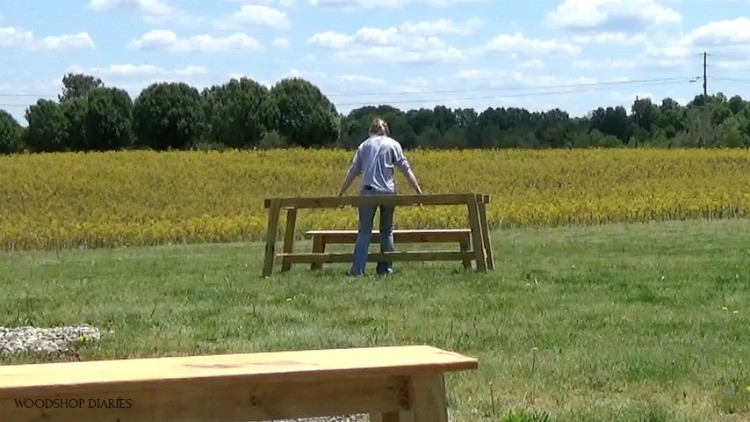 Shara carrying trestle table base and benches out into front yard